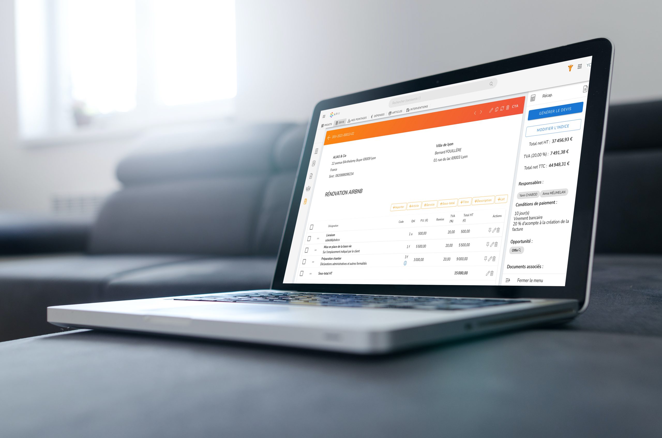 Un ordinateur portable élégant affichant une interface logicielle de gestion financière repose sur un canapé gris. L'écran affiche les détails des transactions, les dates, les montants et les catégories dans une présentation claire et organisée. La lumière éclatante de l'écran contraste avec le mobilier élégant et moderne.